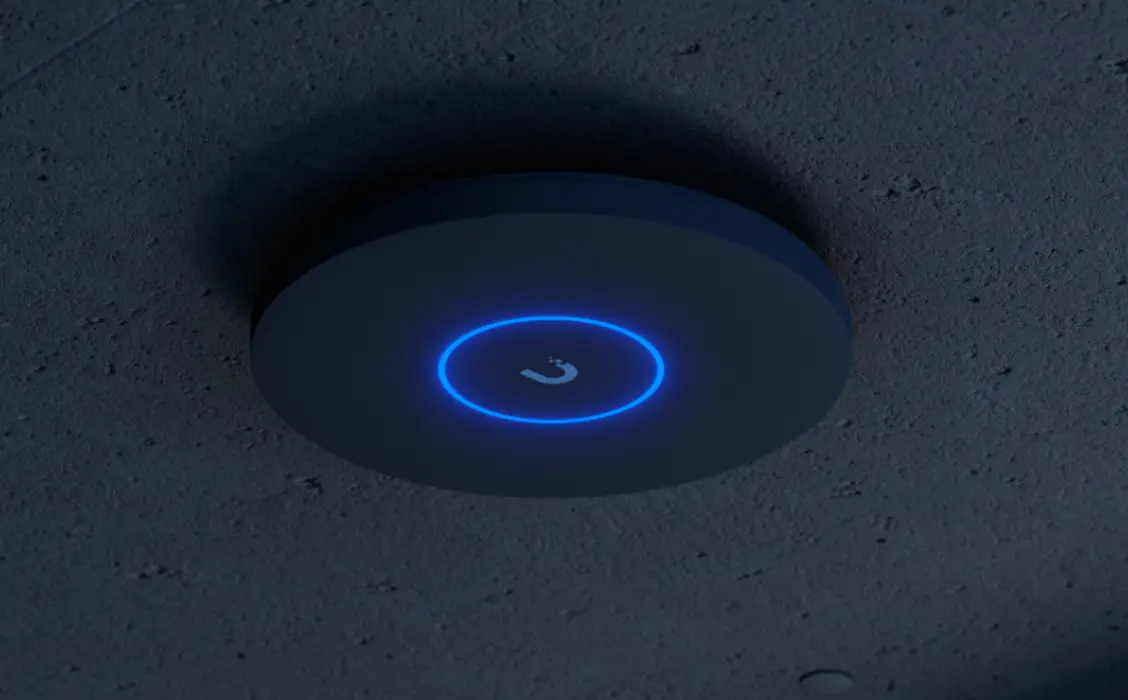 Ubiquiti U7 Pro XG zamontowany na suficie, czarna obudowa świecąca niebieskim pierścieniem LED w ciemnym pomieszczeniu