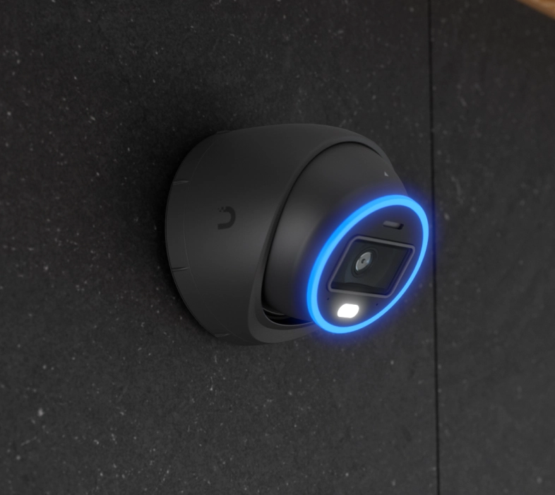 Ubiquiti UVC-AI-Turret zamontowana na ścianie, z niebieskim pierścieniem LED wokół obiektywu