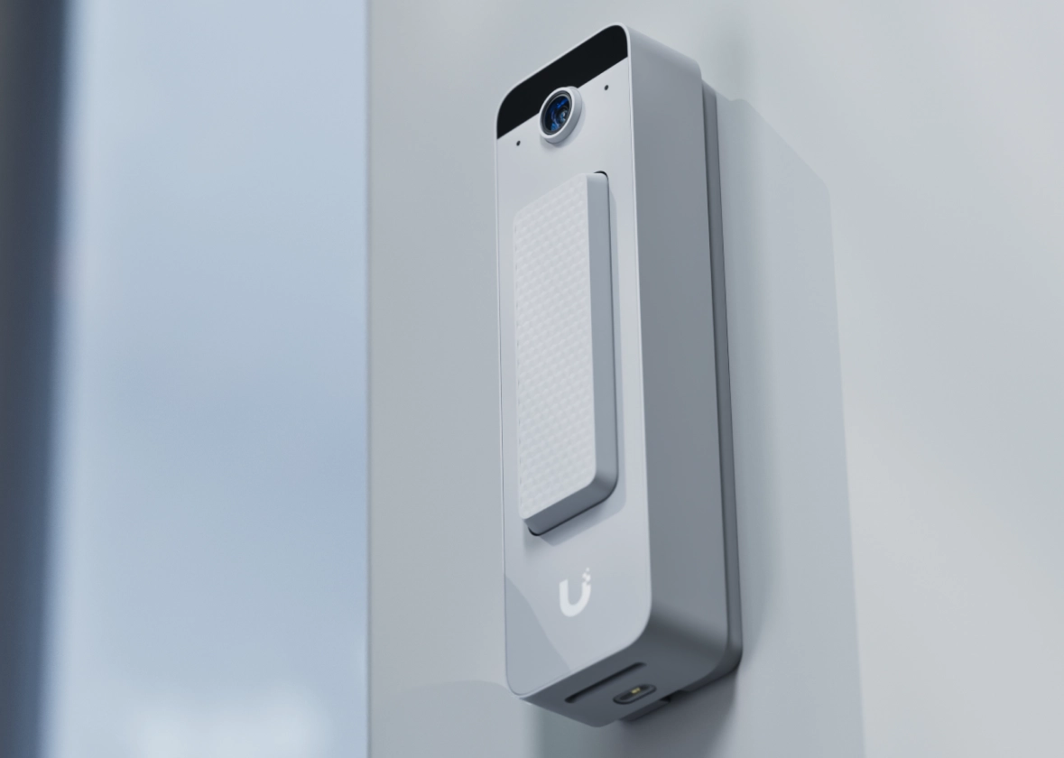 Ubiquiti Doorbell Lite zamontowane na ścianie, z kamerą i przyciskiem w kształcie prostokąta. Obudowa biała