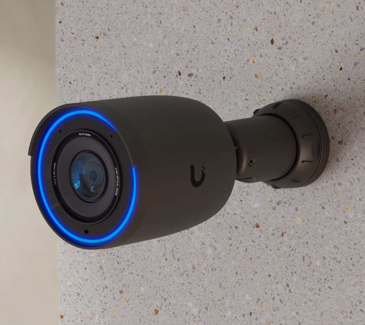 Zainstalowana kamera Ubiquiti UVC-G6 Pro Bullet na ścianie, z niebieskim pierścieniem LED wokół obiektywu